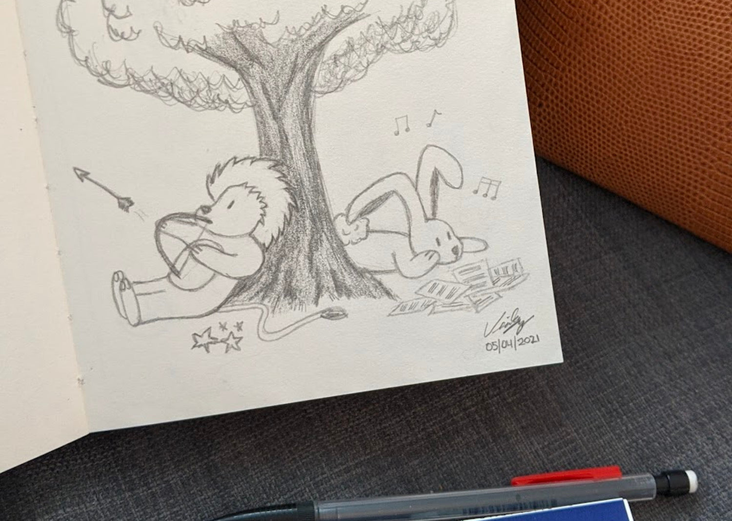 Image of a pencil sketch on a sketchbook of a Lion and a Bunny under a tree